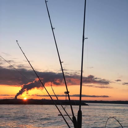 Sunset over water with fishing rod silhouettes